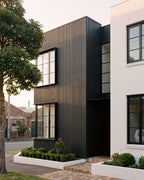 Black timber-look slat panels wrapping a modern home facade with large windows.