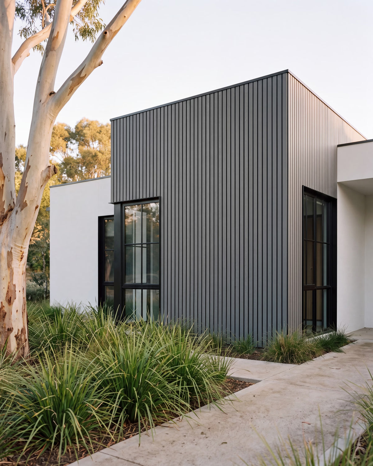 Grey exterior wall panels on an architectural home among native bush.