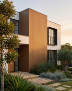 Oak wood-look wall panels on a home exterior with coastal greenery.