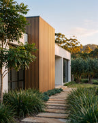 Oak exterior wall panels on a home exterior among greenery.
