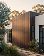 Walnut composite wall panels on a home exterior among greenery.