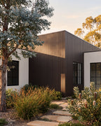 Walnut composite wall panels on a home surrounded by greenery.